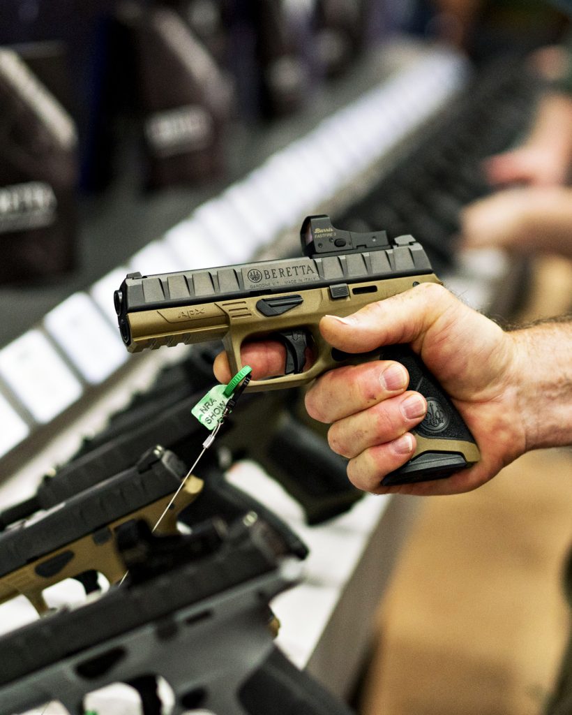 An attendee holds a Fabbrica d'Armi Pietro Beretta SpA pistol at the company's booth during the National Rifle Association annual meeting in Dallas, Texas, on May 5, 2018.